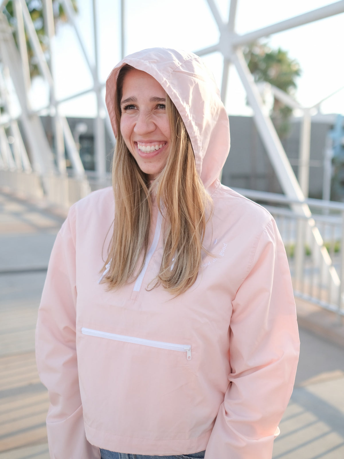Blush Pink Windbreaker with a white zipper and a happy face embroidered on it. The happy face has the words "do good" written on it. This Christian women's jacket is based on Ecclesiastes 3:12 and our brand name Rejoice & Do Good